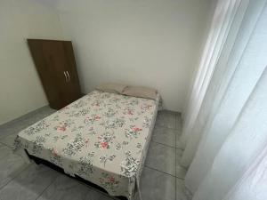 uma pequena cama num quarto com uma colcha floral em Kitnet perto da praia na Praia Grande