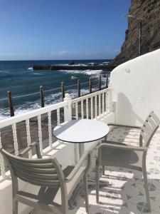 una mesa y sillas sentadas en un balcón con vistas al océano en VV YELYMAR. PLAYA DE ALOJERA en Alojera