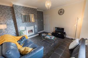 sala de estar con sofá de cuero azul y pared de ladrillo en OG Tranquil Stays- Free WiFi, Office, Free secured parking and garden, en Thornaby on Tees