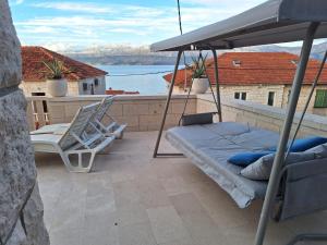 a porch with a bed and a chair on a balcony at Apartments Nada in Postira