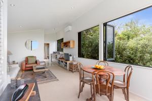 a living room with a table and chairs and large windows at Winemakers Loft in Oneroa