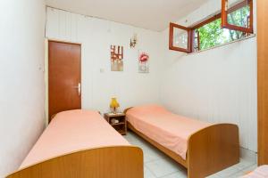 2 łóżka w pokoju z białymi ścianami i oknem w obiekcie Apartments by the sea Seget Vranjica, Trogir - 1038 w mieście Seget Vranjica