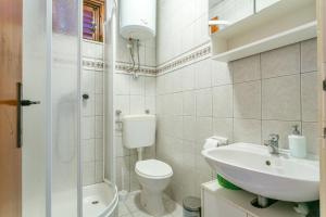 La salle de bains blanche est pourvue de toilettes et d'un lavabo. dans l'établissement Apartments by the sea Seget Vranjica, Trogir - 1038, à Seget Vranjica