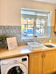 a kitchen with a washing machine and a sink at Oakley Vale House and Garden! Free Private Parking, TV, Fully Equipped in Corby