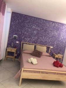 1 dormitorio con 1 cama con pared morada en B&B Al Cavour, en Acireale