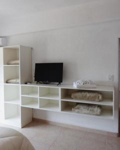 une étagère blanche avec une télévision dans l'établissement Habano Apart, à Esquina