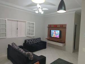 a living room with a couch and a tv at Casa com Piscina e churrasqueira/ mar casado in Guarujá