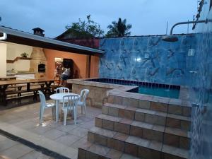 a patio with a swimming pool and a table and chairs at Casa com Piscina e churrasqueira/ mar casado in Guarujá