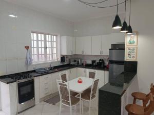 a kitchen with white cabinets and a table and chairs at Casa com Piscina e churrasqueira/ mar casado in Guarujá