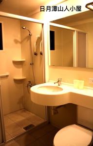 a bathroom with a sink and a toilet and a mirror at Cabin of Sun Moon Lake in Yuchi
