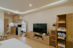 a living room with a large television and a kitchen at Mini Jung koji in Chiang Mai