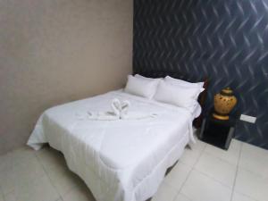 a bedroom with a white bed with white sheets and pillows at Afya Alya Guesthouse Melaka in Melaka