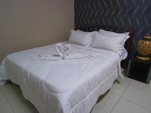 a bed with a white comforter with a bow on it at Afya Alya Guesthouse Melaka in Melaka