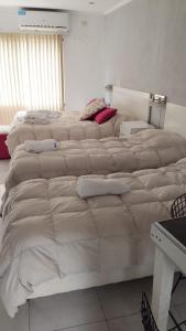 Duas camas grandes num quarto com lençóis brancos em DINASTIE APART HOTEL em Chajarí