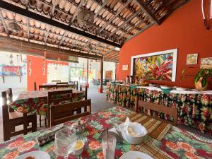 a restaurant with tables and chairs and orange walls at Pousada Vôo da Águia in Itacaré