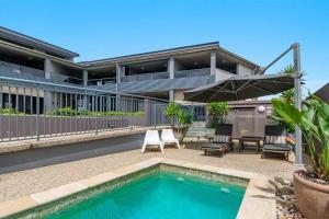 a house with a swimming pool with chairs and an umbrella at Sea Spray - Lennox Head in Lennox Head