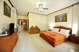 a bedroom with a bed and a couch and a television at Tori Inn in Sanur