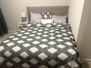 um quarto com uma cama com um edredão preto e branco em TN Homes em Ottawa