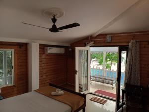 1 dormitorio con 1 cama y ventilador de techo en Peles Windsong wooden cottages, en Benaulim