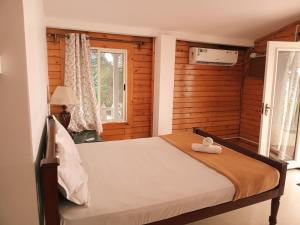 1 dormitorio con 1 cama en una habitación con paredes de madera en Peles Windsong wooden cottages, en Benaulim