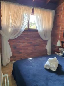 a bedroom with a blue bed with curtains and a window at Duplex estilo europeu Ednamar Apartamentos Bérgamo in Gramado