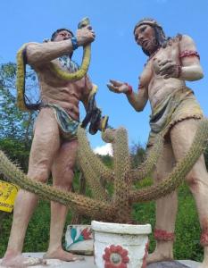 Una estatua de dos hombres parados junto a un cactus en Mirante toca da raposa, en Meruoca