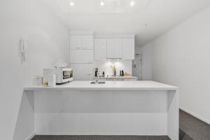 cocina blanca con fregadero y microondas en Southbank Two Bedroom Apt - 2202 en Melbourne