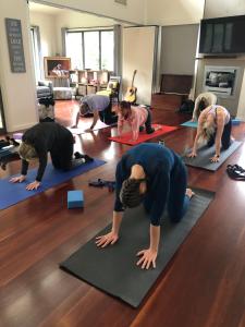 a group of people doing yoga in a living room at Tranquil Getaways On Obi Maleny in Maleny