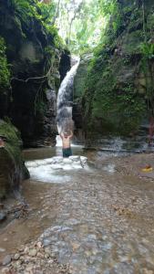 a man standing in a stream in front of a waterfall at Centro Arte Terapéutico San Isidro Glamping in San Isidro