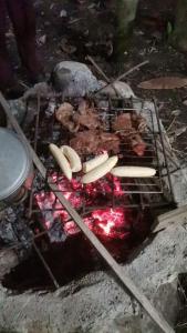 una parrilla con perritos calientes y carne. en Centro Arte Terapéutico San Isidro Glamping en San Isidro