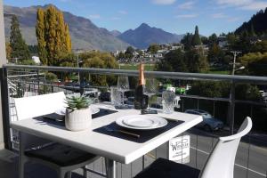 a white table with a bottle of wine on a balcony at Very Close to Town- Mountain Views in Queenstown