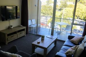 a living room with a couch and a tv and a balcony at Very Close to Town- Mountain Views in Queenstown