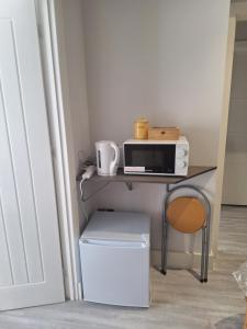 a desk with a microwave and a table with a chair at Budget Single room only for one adult in Northolt