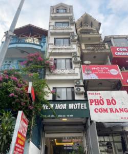 ein hohes weißes Gebäude mit Schildern davor in der Unterkunft YÊN HÒA MOTEL in Hanoi
