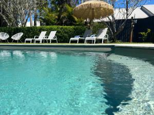 a group of chairs and an umbrella and a swimming pool at The Arabella North Coast in Wollongbar