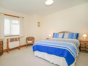 a bedroom with a blue and white bed and a window at Gelli Gron open Pastures in Llangybi