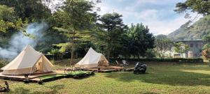 a group of tents in a field with smoke at Umarin Glamping Resort in Ban Huai Sok Noi