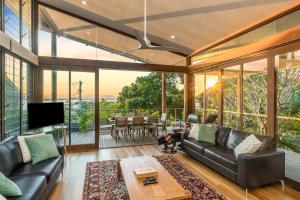 a living room with a couch and a tv at Above The Pass in Byron Bay