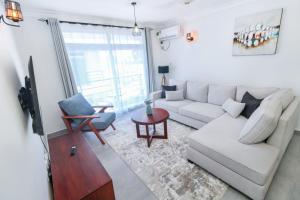 ein Wohnzimmer mit einem weißen Sofa und einem TV in der Unterkunft Serene 3br Apartment in Nyali-Has Swimming pool and AC in Mombasa