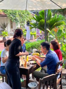 een groep mensen die aan een tafel zitten te eten bij Thom's House in Ninh Binh