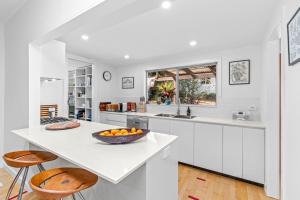 a white kitchen with a bowl of oranges on a counter at Durras Cottage managed by Batemans Bay Accom in Durras