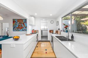 a kitchen with white counters and a large window at Durras Cottage managed by Batemans Bay Accom in Durras +6 photos