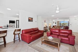 a living room with a red couch and a table at Solnamara - Hosted by Burleigh Letting in Gold Coast