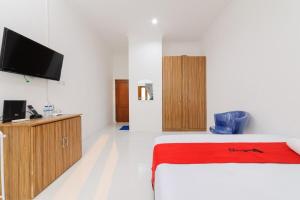Schlafzimmer mit einem Bett und einem Flachbild-TV in der Unterkunft RedDoorz Syariah @ Sakura Hotel Duren Sawit 