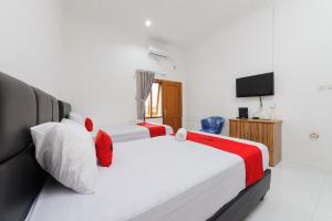ein Hotelzimmer mit 2 Betten und einem TV in der Unterkunft RedDoorz Syariah @ Sakura Hotel Duren Sawit 