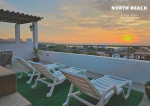 un grupo de sillas en un balcón con vistas a la puesta de sol en Casa Norte North Beach, en Los Órganos