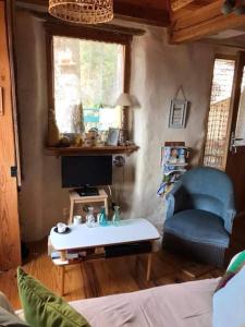 ein Wohnzimmer mit einem TV und einem blauen Stuhl in der Unterkunft Maisonnette avec terrasse et vue imprenable in Théus