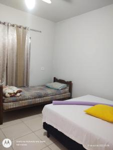 ein Schlafzimmer mit zwei Betten und einem Fenster in der Unterkunft Casa amarela cantinho de lazer in Ilha Comprida