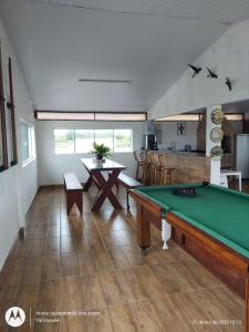 ein Wohnzimmer mit einem Billardtisch und eine Küche in der Unterkunft Casa amarela cantinho de lazer in Ilha Comprida