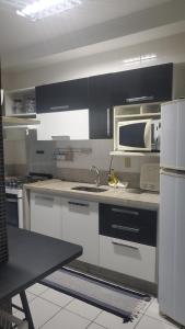 a kitchen with a sink and a microwave at Guarujá - Praia do Tombo - Apartamento in Guarujá